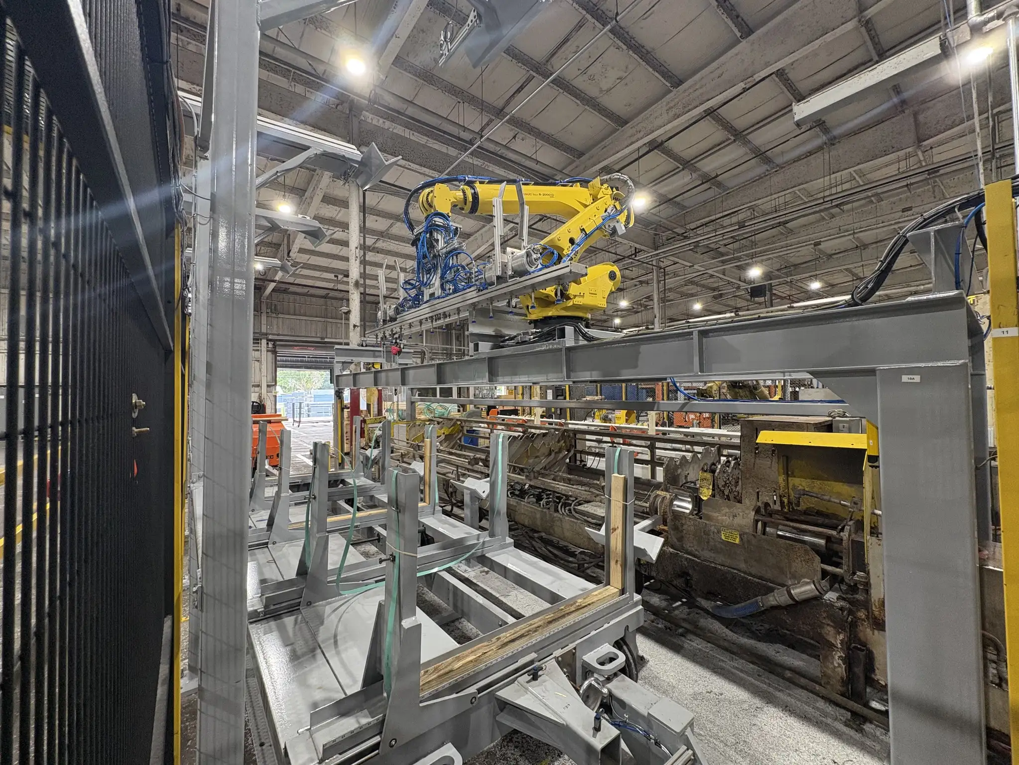 Industrial robotic product handling system installed above production equipment